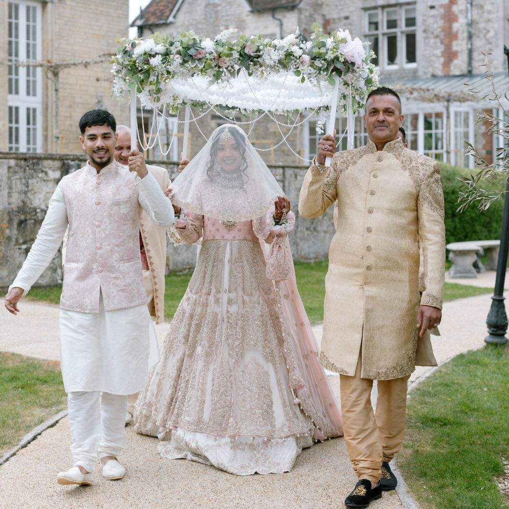 A Bride being walked down the aisle by family members during their Muslim wedding ceremony at Froyle Park, a Pakistani Wedding Venue near London