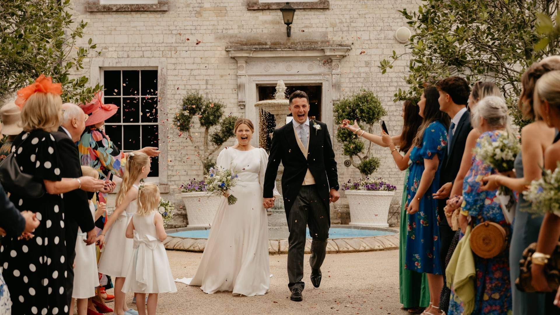 A Bride and Groom enjoy a confetti procession in front of Froyle Park